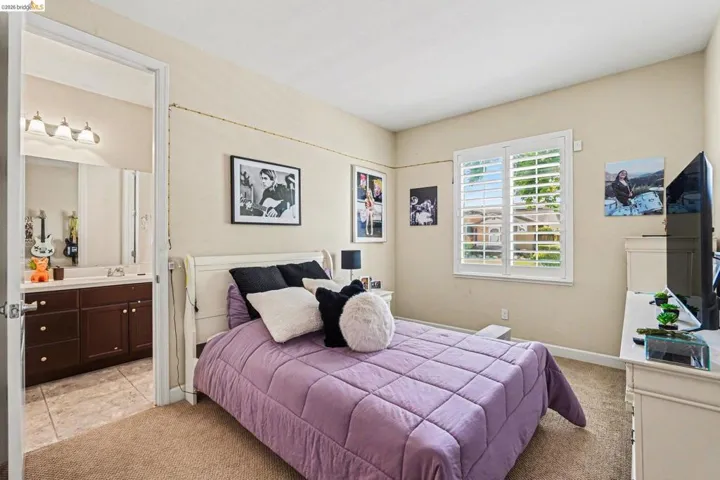 Bedroom featuring light carpet and ensuite bath