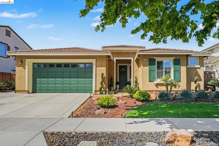 View of front of home with stucco siding, an attached garage, concrete driveway, and a tiled roof