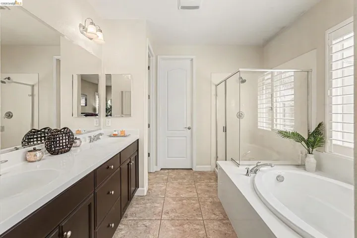 Bathroom with a stall shower, double vanity, a bath, and light tile patterned flooring