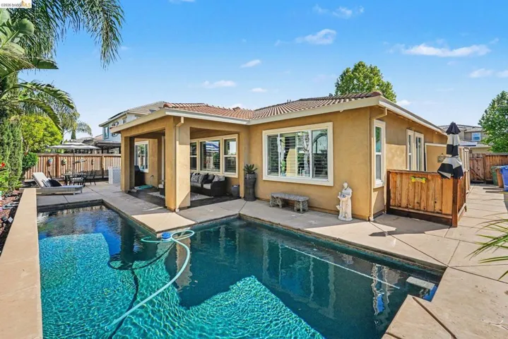Rear view of house with stucco siding, a patio area, a fenced backyard, a tiled roof, and outdoor furniture