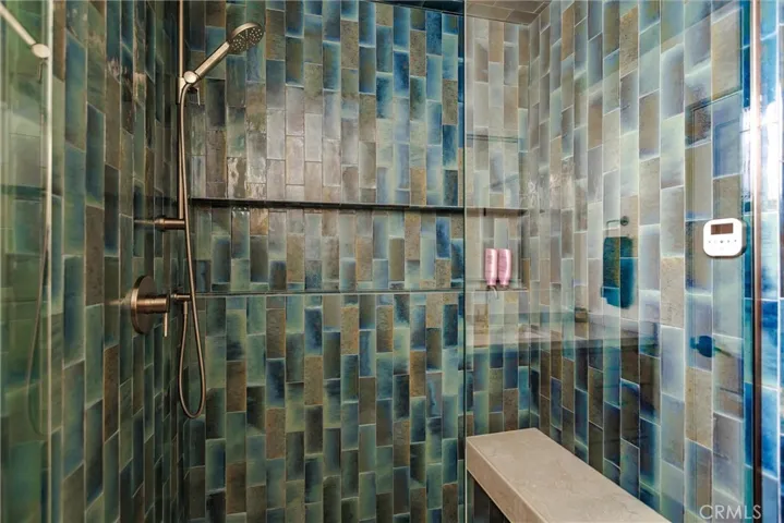 Tesoro glossy tile in Gleeze Turchese is evokes the experience of water in this steam shower with cantilevered bench seat and expansive niche.