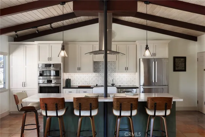 Island has induction stove, Taj Mahal stone slab counters and one-off custom verde colorization