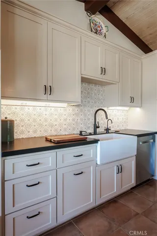 Apron-front sink; Carrara marble backsplash accentuated by black granite countertop; soft-close custom cabinetry