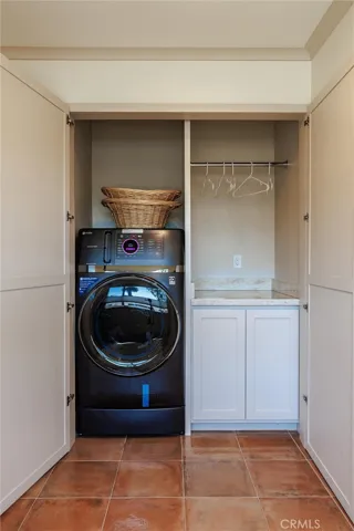 Matching cabinetry, stone counters and a rod for hanging laundry fresh from the machine
