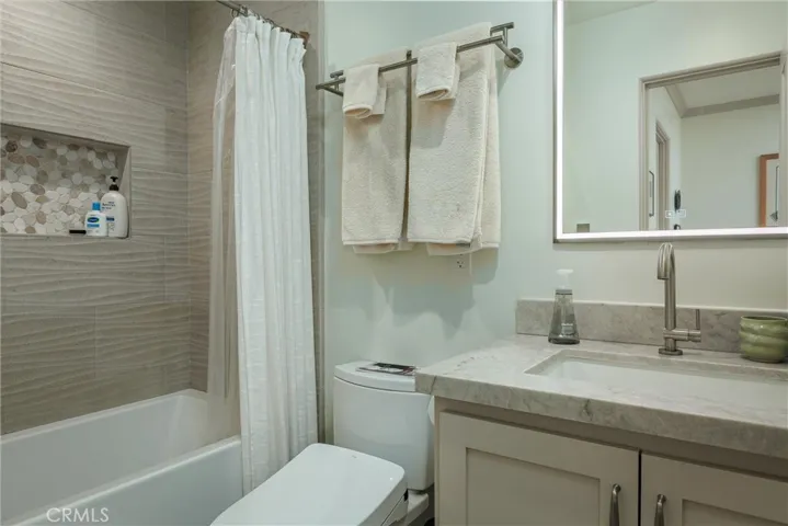 A sand-colored shower surround with wave-shaped tile evoke the coastal influence; built with a wide niche for toiletries. Bathroom includesToto bidet Tolet, deep tub, Madeli lighted bathroom mirror with interior outlet, defog feature and multiple Kelvin settings
