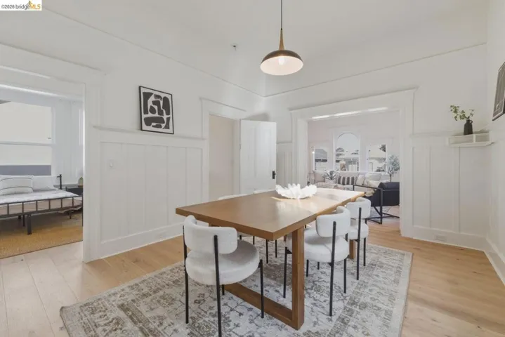 Dining space with a decorative wall, light wood-style flooring, and a wainscoted wall