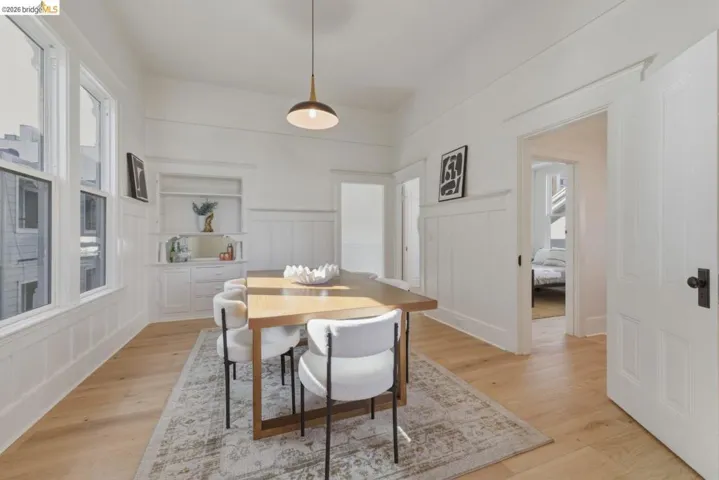 Dining space featuring a decorative wall, wainscoting, and light wood-style floors