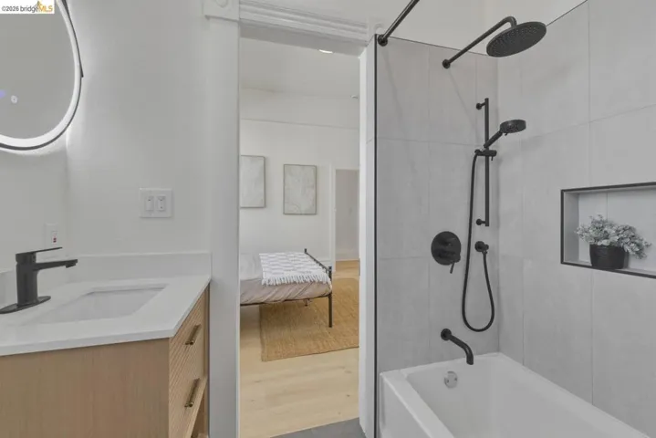 Ensuite bathroom with vanity, shower / bath combo, and light wood-style flooring