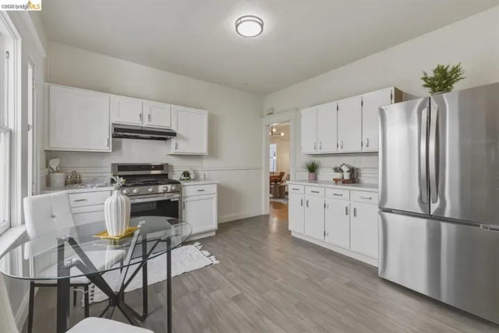 Kitchen featuring stainless steel appliances, light countertops, white cabinets, and light wood-style flooring