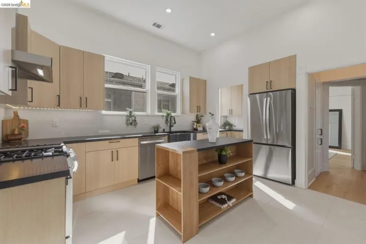 Kitchen featuring open shelves, stainless steel appliances, a kitchen island, light wood finish cabinetry, and decorative backsplash