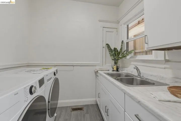 Laundry area featuring wainscoting, separate washer and dryer, dark wood finished floors, and cabinet space
