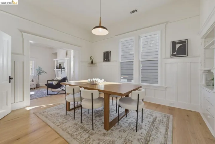Dining area with a decorative wall, light wood finished floors, and a wainscoted wall