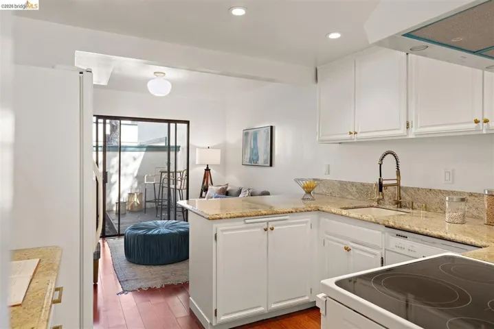 Kitchen featuring white appliances, range hood, a peninsula, white cabinets, and recessed lighting
