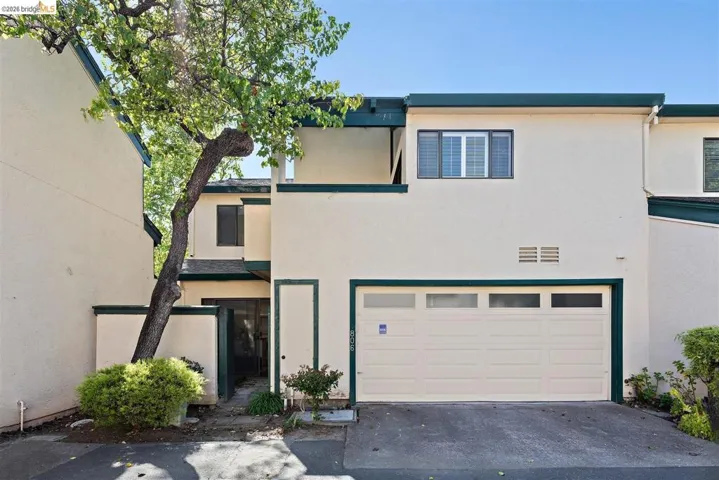Traditional-style house with stucco siding, a garage, and driveway