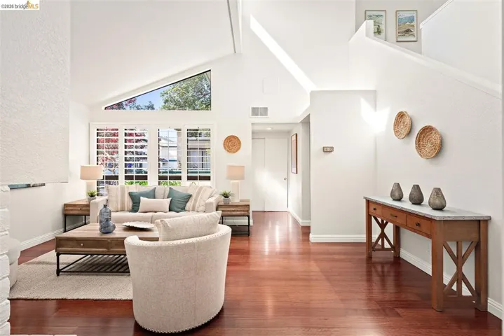Living room with wood finished floors, lofted ceiling, and a textured wall