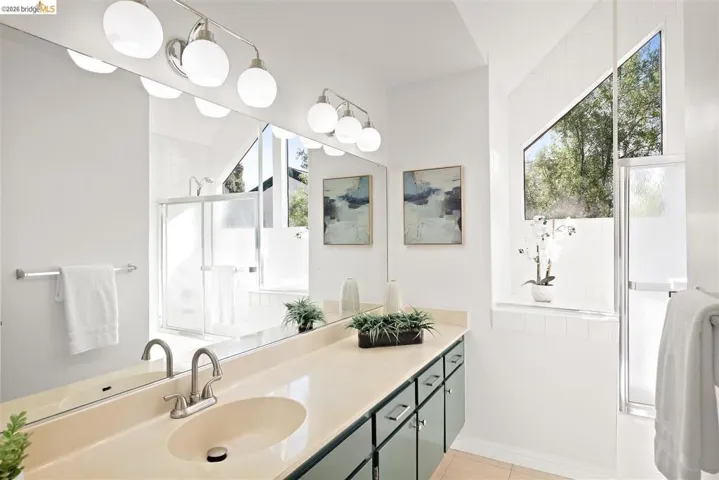 Full bath with a shower stall, vanity, and light tile patterned flooring