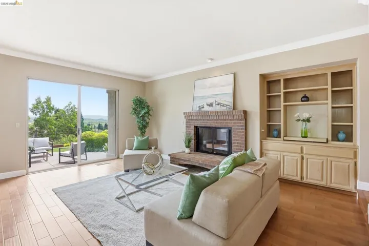 Living room featuring a fireplace, light wood-type flooring, and crown molding
