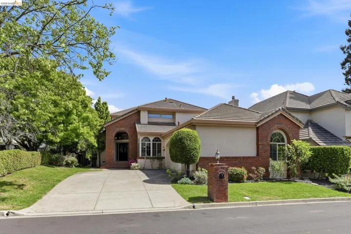 View of front facade with a front lawn, a tiled roof, and brick siding