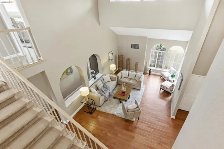 Living area with hardwood / wood-style floors, arched walkways, and a high ceiling