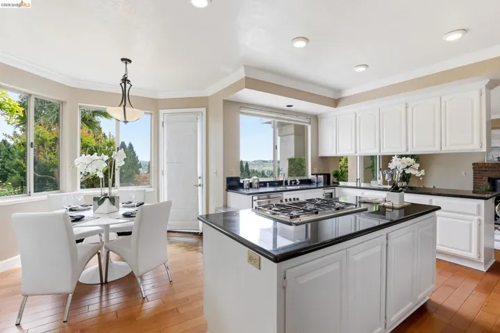 Kitchen with white cabinets, crown molding, a kitchen island, decorative light fixtures, and light wood-style flooring