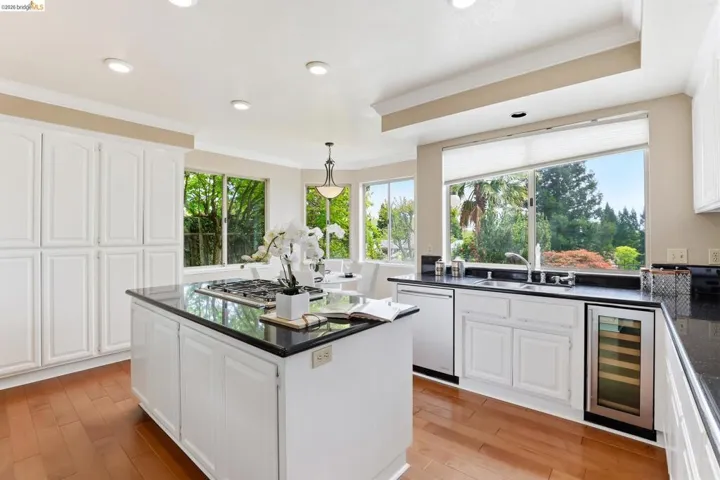 Kitchen featuring white cabinets, beverage cooler, pendant lighting, crown molding, and stainless steel appliances