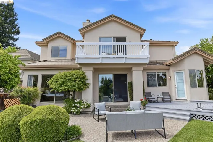 Rear view of house with an outdoor hangout area, a balcony, stucco siding, and a patio