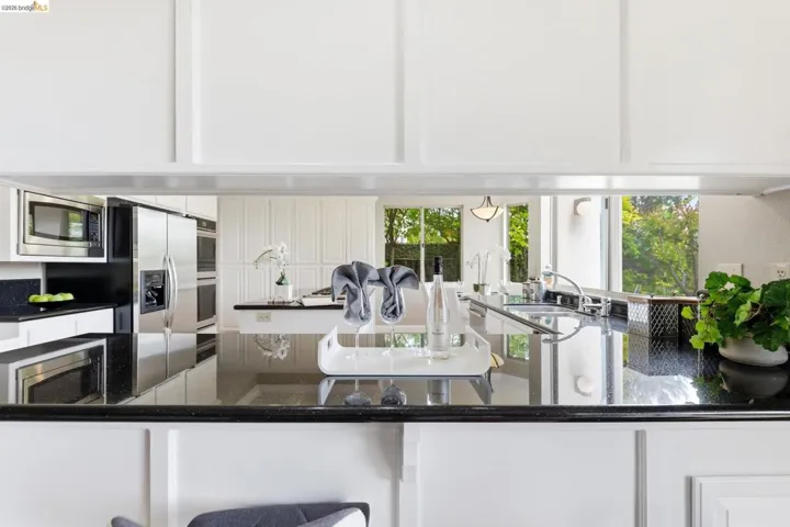 Kitchen with dark stone counters, stainless steel appliances, and white cabinets