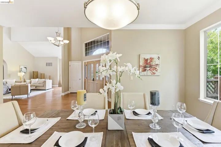Dining space featuring wood finished floors, suspended lighting, a high ceiling, and arched walkways
