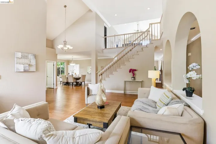 Living room with a high ceiling, light wood-type flooring, crown molding, and a chandelier