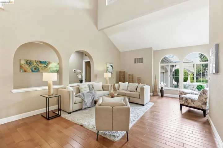 Living area with light wood-type flooring, a high ceiling, and arched walkways