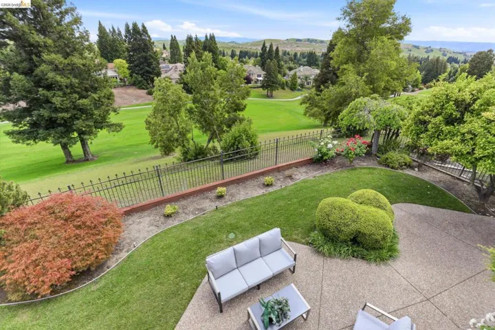 Fenced backyard with view of golf course and a patio area