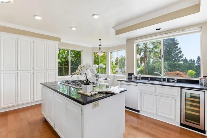Kitchen with white cabinets, beverage cooler, pendant lighting, stainless steel appliances, and light wood-style floors