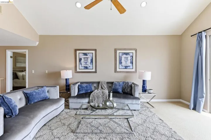 Living area featuring ceiling fan, lofted ceiling, and light carpet