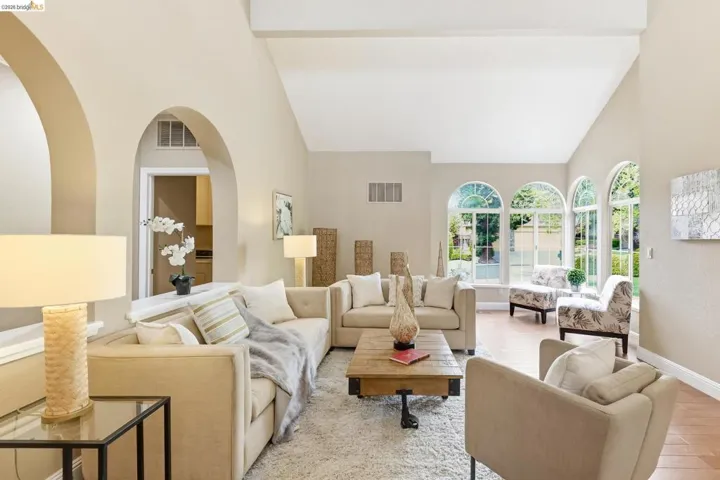 Living room featuring vaulted ceiling, wood finished floors, and arched walkways