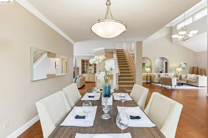 Dining space featuring wood finished floors, crown molding, suspended lighting, and arched walkways