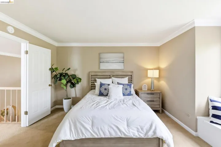 Bedroom with ornamental molding and light carpet