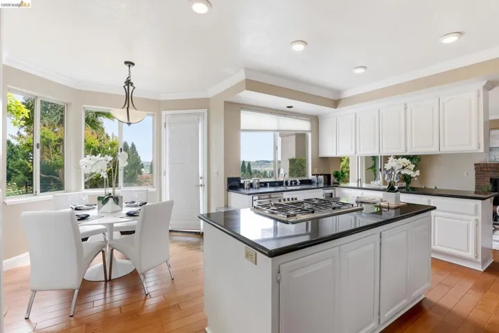 Kitchen with white cabinetry, a center island, ornamental molding, light wood-type flooring, and pendant lighting