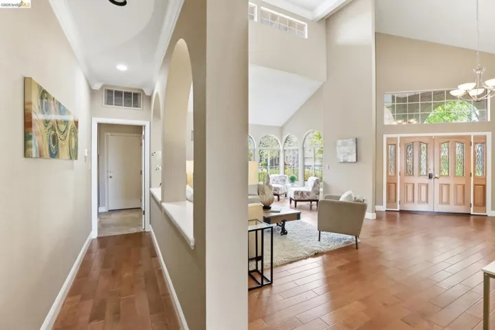 Corridor featuring wood finished floors, crown molding, hanging lights, and a high ceiling