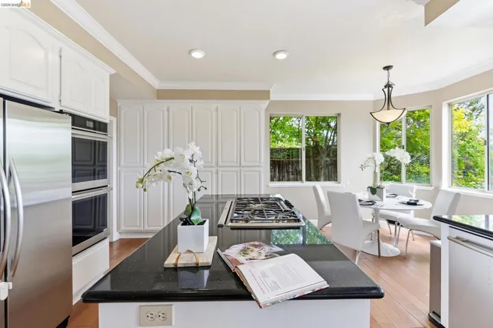 Kitchen with white cabinetry, stainless steel appliances, dark stone countertops, and crown molding