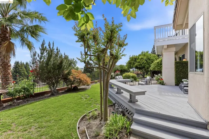 Fenced backyard featuring a wooden deck and a balcony
