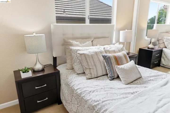 Bedroom with light carpet, a textured wall, and multiple windows