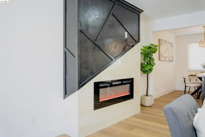 Living room with light wood-style floors, a tiled fireplace, and suspended lighting