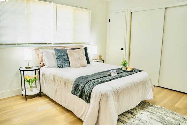 Bedroom with light wood-style flooring, multiple windows, and a closet