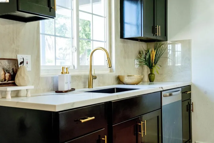 Kitchen featuring light stone counters, dishwasher, and tasteful backsplash