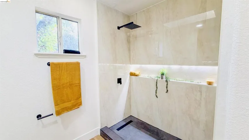 Full bathroom featuring a marble finish shower and a textured wall