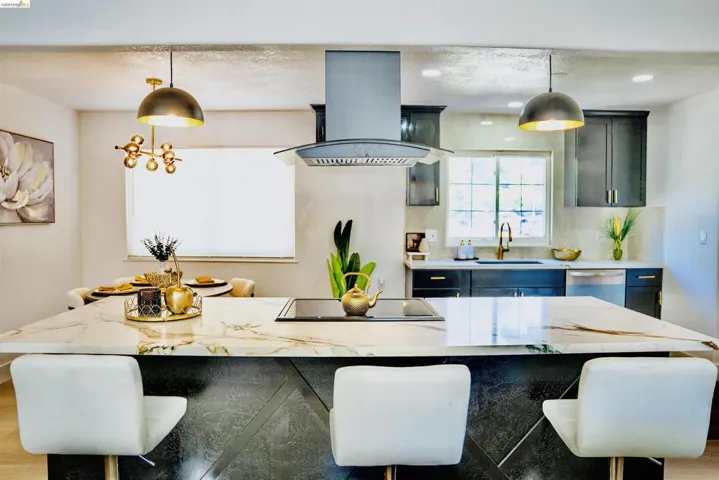 Kitchen with a kitchen bar, island range hood, light stone countertops, dishwasher, and pendant lighting