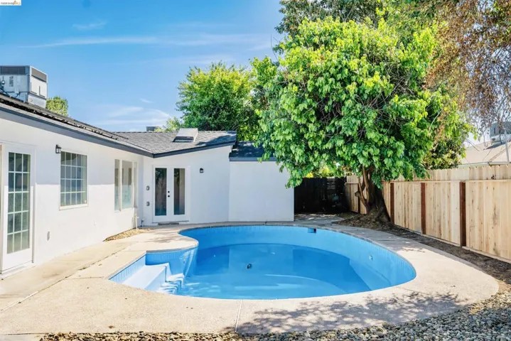 View of swimming pool featuring french doors, a fenced backyard, and patio surround