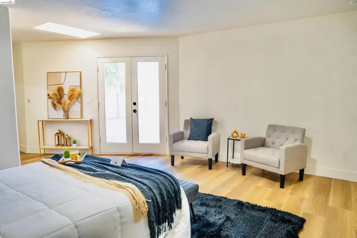 Bedroom featuring light wood finished floors, french doors, access to outside, and a skylight