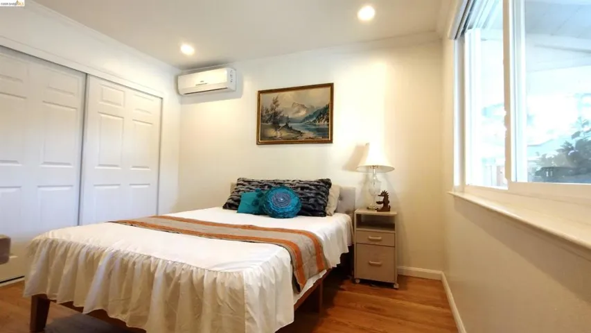 Bedroom featuring dark wood-type flooring, a closet, crown molding, and recessed lighting