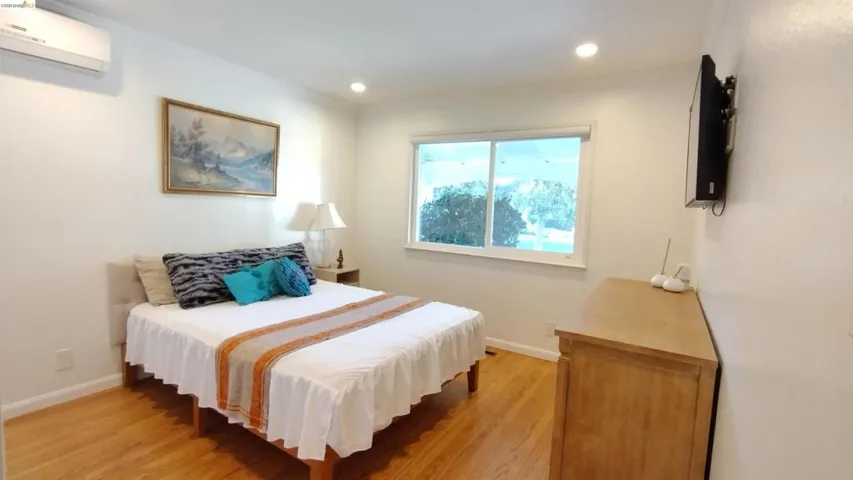 Bedroom with a mini split for heating / cooling, light wood-style floors, and recessed lighting